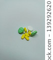 Top view of a small pile of green, yellow, and white medicine pills scattered on a plain white background 139292620