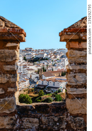 View of the town of Ronda, Spain, through a loophole in an ancient stone wall. View of the town of Ronda, Spain, through a loophole in an ancient stone wall. 139292795