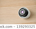Close-up view of a water bottle cap with UV light mounted on a light wooden surface, highlighting precision water cleaning, reusable health technology and creative projects. 139293325