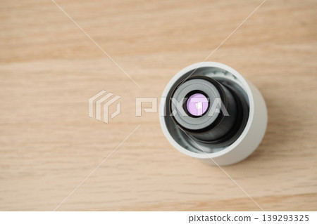 Close-up view of a water bottle cap with UV light mounted on a light wooden surface, highlighting precision water cleaning, reusable health technology and creative projects. 139293325