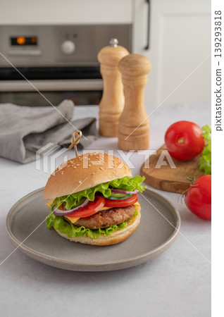 Beef burger with tomato, cheese, and lettuce on a plate on a kitchen table with spice Beef burger with tomato, cheese, and lettuce on a plate on a kitchen table with spice 139293818
