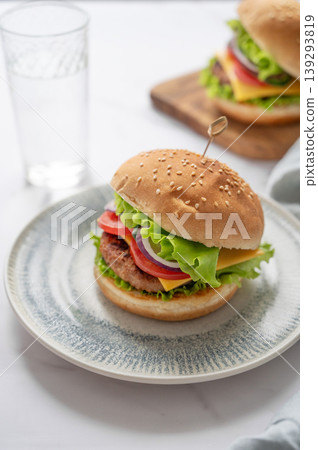 Two Beef burgers with tomato, cheese, and lettuce on a plate on a marble background 139293819