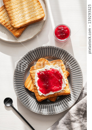 Toast with sweet berry-fruit jam and cream cheese on a plate on a white wooden background with spoon Toast with sweet berry-fruit jam and cream cheese on a plate on a white wooden background with spoon 139293825