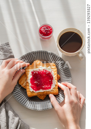 Hand holding toast with sweet berry-fruit jam and cream cheese on a plate on a white background Hand holding toast with sweet berry-fruit jam and cream cheese on a plate on a white background 139293827