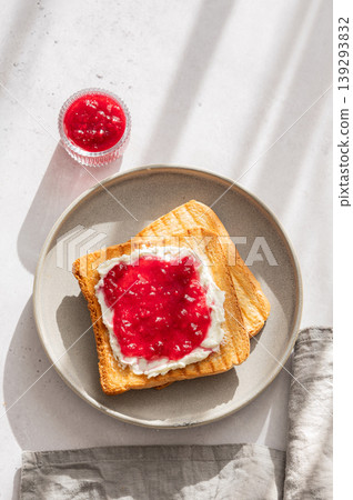 Toast with sweet berry-fruit jam and cream cheese on a plate on a light concrete background Toast with sweet berry-fruit jam and cream cheese on a plate on a light concrete background 139293832