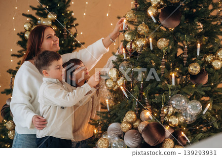 Woman with son and daughter are decorating the Christmas tree at home Woman with son and daughter are decorating the Christmas tree at home 139293931