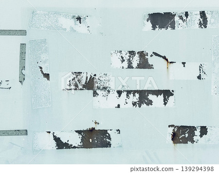 The texture of an old metal wall with peeling paint and tape marks. 139294398