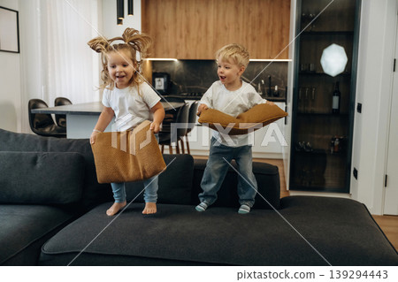 Boy and girl are playing on the black sofa at home, having fun Boy and girl are playing on the black sofa at home, having fun 139294443