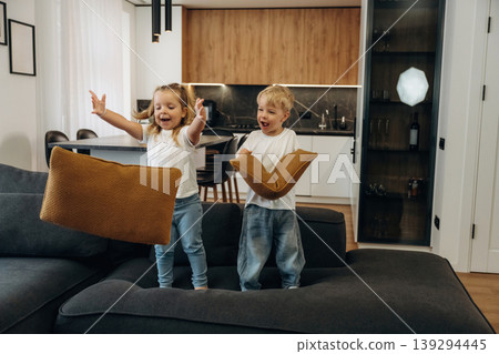 Boy and girl are playing on the black sofa at home, having fun 139294445