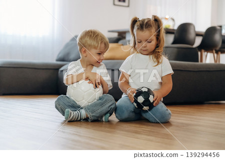 Soccer balls, conception of sport. Little kids are playing together in the domestic room at daytime Soccer balls, conception of sport. Little kids are playing together in the domestic room at daytime 139294456