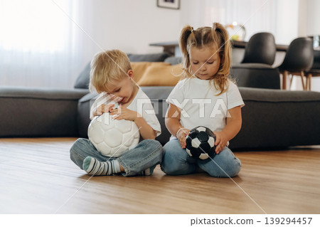 Soccer balls, conception of sport. Little kids are playing together in the domestic room at daytime Soccer balls, conception of sport. Little kids are playing together in the domestic room at daytime 139294457