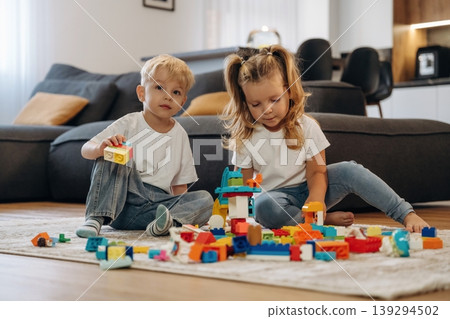 Two kids are playing with construction blocks toys at home Two kids are playing with construction blocks toys at home 139294502