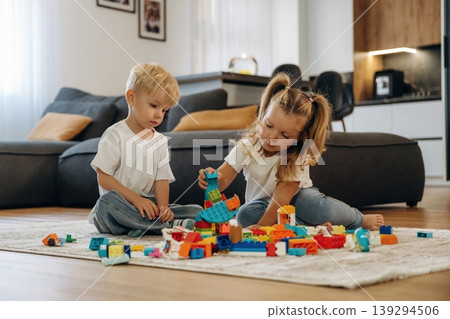 Building the tower, sitting. Two kids are playing with construction blocks toys at home 139294506