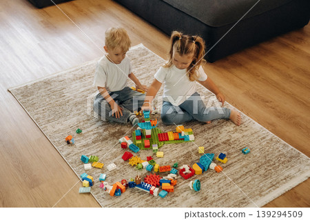 Sitting on the modern carpet. Two kids are playing with construction blocks toys at home 139294509