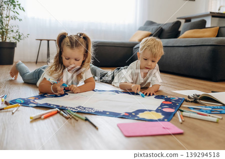 Learning how to draw. Little kids are playing together in the domestic room at daytime Learning how to draw. Little kids are playing together in the domestic room at daytime 139294518