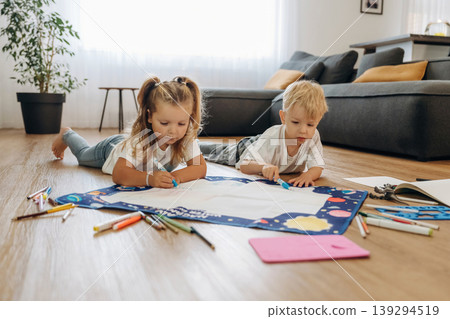 Learning how to draw. Little kids are playing together in the domestic room at daytime Learning how to draw. Little kids are playing together in the domestic room at daytime 139294519
