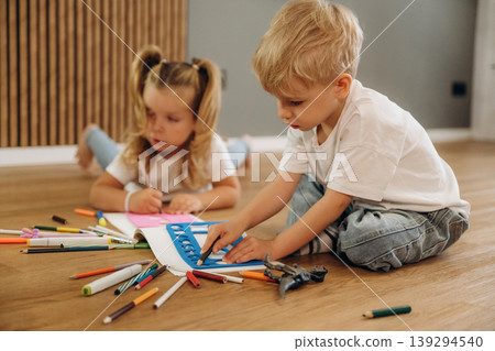 Process of drawing. Little kids are playing together in the domestic room at daytime Process of drawing. Little kids are playing together in the domestic room at daytime 139294540