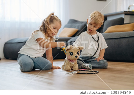 Stethoscope, doctors with plush toy. Little kids are playing together in the domestic room at daytime Stethoscope, doctors with plush toy. Little kids are playing together in the domestic room at daytime 139294549