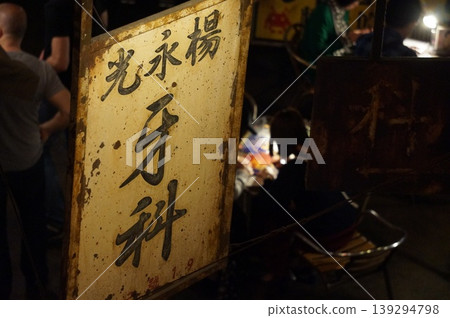 一間鏽跡斑斑的舊牙醫診所，掛著中文招牌，位於一條讓人想起九龍城寨的小巷裡。 139294798