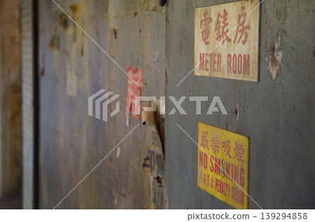 A meter room and an old no-smoking sign in a dilapidated wall reminiscent of Kowloon Walled City. 139294858