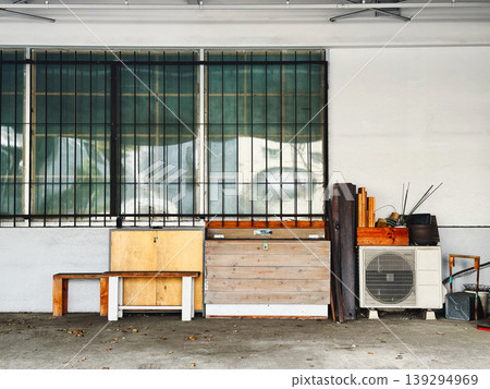 A scene with wooden furniture and an outdoor air conditioning unit placed under the eaves of an old garage. A scene with wooden furniture and an outdoor air conditioning unit placed under the eaves of an old garage. 139294969