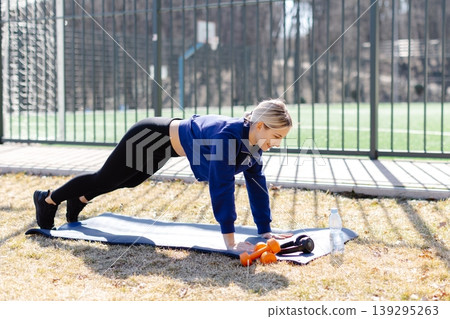 Sportswoman performing side plank exercise outdoors Sportswoman performing side plank exercise outdoors 139295263