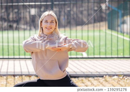 Young woman performing yoga exercises in a park near a soccer field Young woman performing yoga exercises in a park near a soccer field 139295276