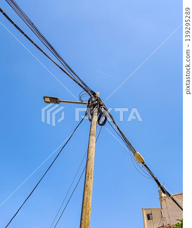 Wooden Street Lamp with Multiple Cables and Buildings Under Blue Sky 139295289