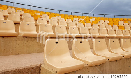 Rows of Empty Yellow and White Seats in Outdoor Stadium 139295291