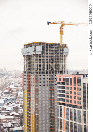 Construction of a modern high-rise building with crane in a snowy urban landscape during winter Construction of a modern high-rise building with crane in a snowy urban landscape during winter 139296009