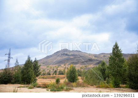 Mountain landscape with electricity pylons and green bushes. Eco-restoration and reclamation of industrial areas for improved environmental conditions and quality of life. Mountain landscape with electricity pylons and green bushes. Eco-restoration and reclamation of industrial areas for improved environmental conditions and quality of life. 139296011