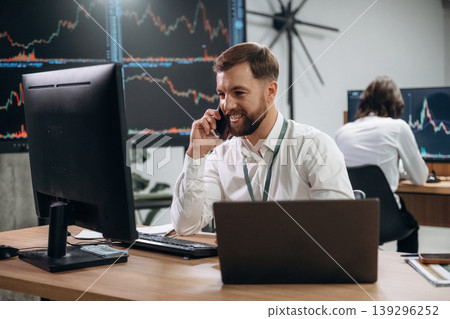 Making a call, talking by a phone. Two male exchange workers are in the office together 139296252