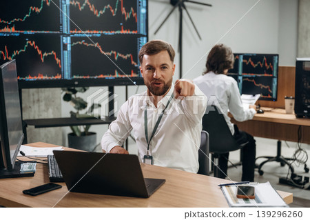 Pointing the finger at you, camera. Two male exchange workers are in the office together Pointing the finger at you, camera. Two male exchange workers are in the office together 139296260
