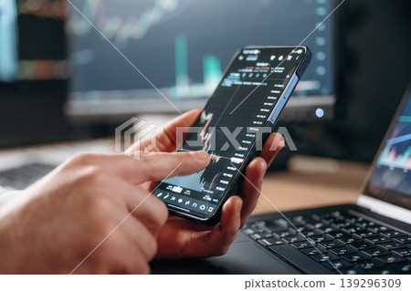 Detailed close up view of man's hands that is holding smartphone with stock market crypto information 139296309
