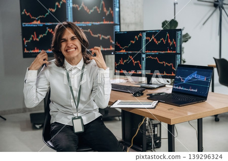 Young man is sitting in the office with multiple displays of stock market data Young man is sitting in the office with multiple displays of stock market data 139296324