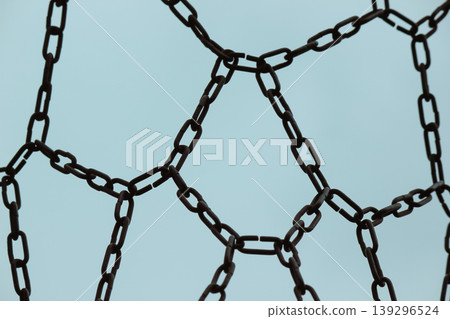 Silhouette of a metal chain basketball net pattern against a clear blue sky background 139296524