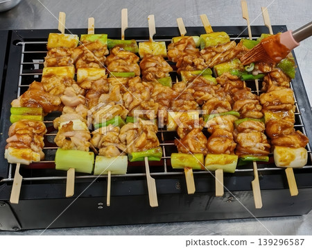 Japanese Yakitori Chicken Skewers with Scallions Being Grilled and Brushed with Teriyaki Sauce 139296587