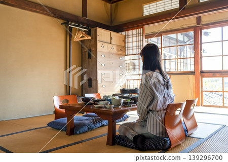 女兒在一家傳統的日本旅館裡,坐在擺放著懷石料理的桌子前等待父母。 女兒在一家傳統的日本旅館裡,坐在擺放著懷石料理的桌子前等待父母。 139296700