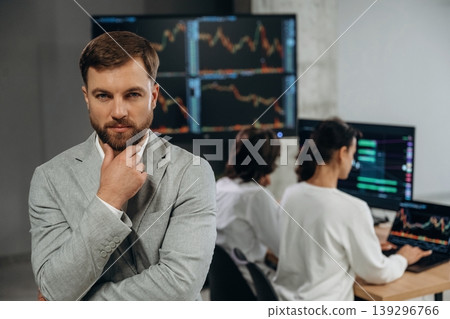 Looking at the camera, CEO is standing. Business people are working with stock market exchange in office Looking at the camera, CEO is standing. Business people are working with stock market exchange in office 139296766