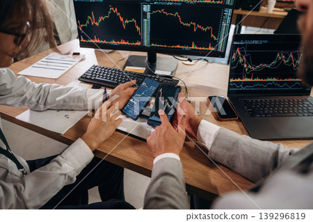 Comparing the data. Close up view of hands of business men that are working with stock market exchange 139296819