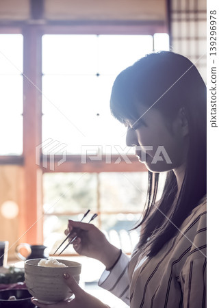 一位年輕女子在傳統的日式旅館裡享用日本料理,鏡頭捕捉到她的側臉。 一位年輕女子在傳統的日式旅館裡享用日本料理,鏡頭捕捉到她的側臉。 139296978