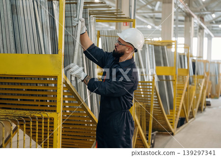 Bunch of raw windows parts. Warehouse worker in an industrial environment of a factory or storage area Bunch of raw windows parts. Warehouse worker in an industrial environment of a factory or storage area 139297341
