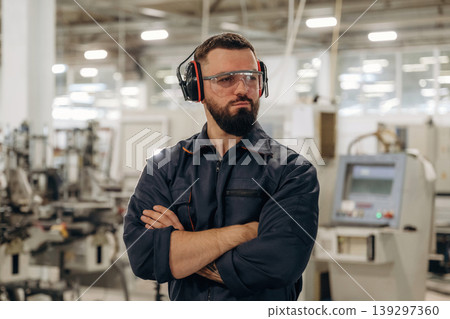 Break time, standing with arms crossed. Warehouse worker in an industrial environment of a factory or storage area Break time, standing with arms crossed. Warehouse worker in an industrial environment of a factory or storage area 139297360