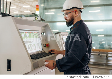 Side view, machine operator is standing and working. Warehouse worker in an industrial environment of a factory or storage area Side view, machine operator is standing and working. Warehouse worker in an industrial environment of a factory or storage area 139297386