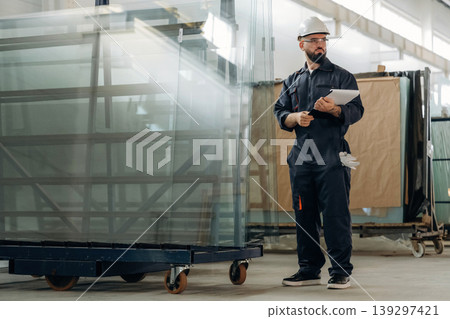 Glass is ready to put in windows. Warehouse worker in an industrial environment of a factory or storage area Glass is ready to put in windows. Warehouse worker in an industrial environment of a factory or storage area 139297421