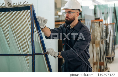 Glass is ready to put in windows. Warehouse worker in an industrial environment of a factory or storage area Glass is ready to put in windows. Warehouse worker in an industrial environment of a factory or storage area 139297422
