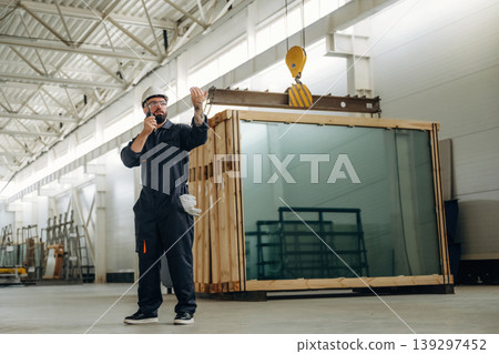 Talking by walkie talkie. Warehouse worker in an industrial environment of a factory or storage area Talking by walkie talkie. Warehouse worker in an industrial environment of a factory or storage area 139297452