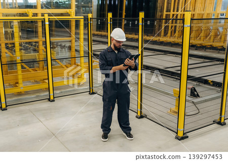 Holding digital tablet. Warehouse worker in an industrial environment of a factory or storage area Holding digital tablet. Warehouse worker in an industrial environment of a factory or storage area 139297453