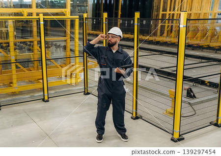 Holding digital tablet. Warehouse worker in an industrial environment of a factory or storage area 139297454