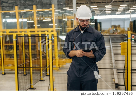 Holding digital tablet. Warehouse worker in an industrial environment of a factory or storage area Holding digital tablet. Warehouse worker in an industrial environment of a factory or storage area 139297456